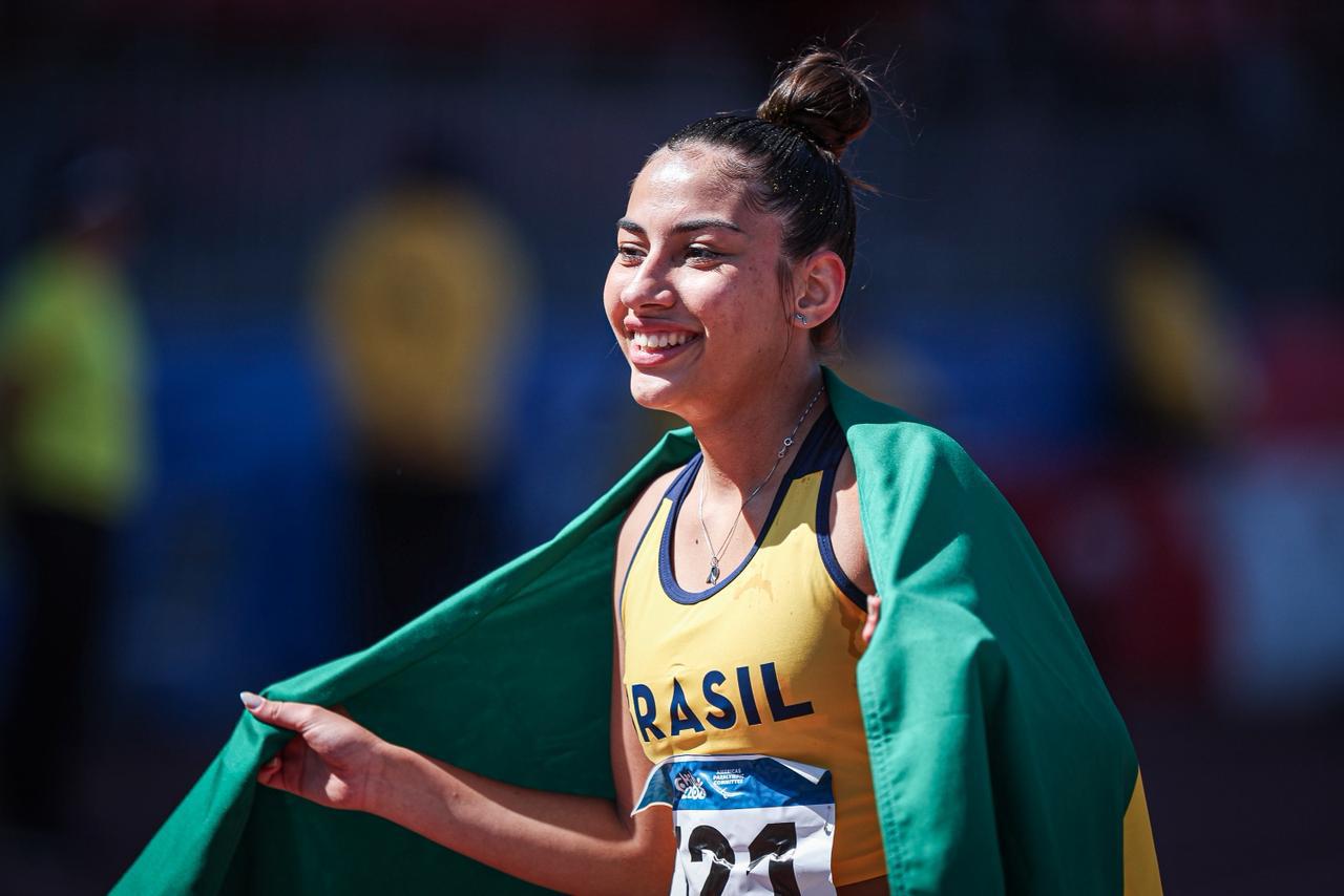 Geovana Fanton sorri com a bandeira do Brasil sobre os ombros, em foto de arquivo.