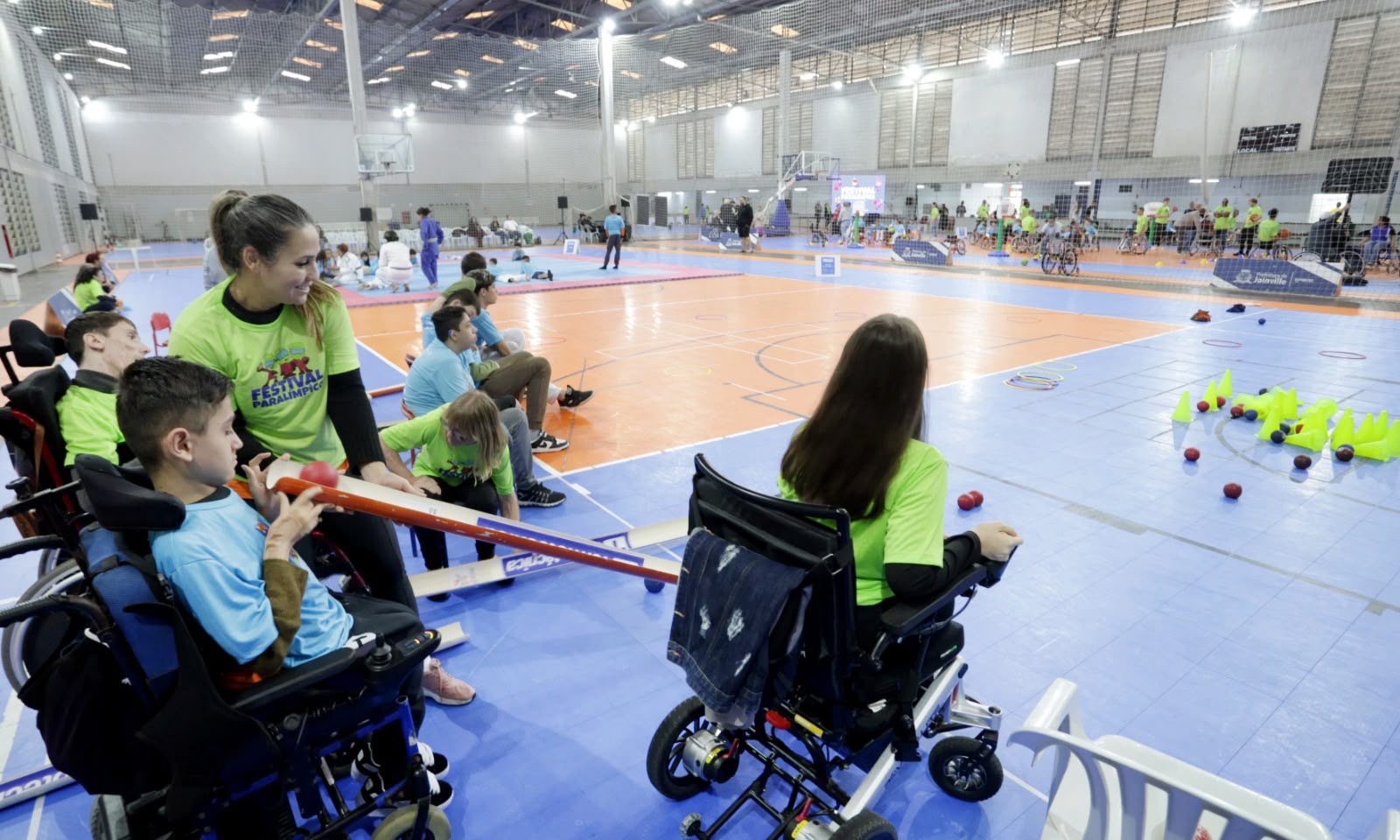Participantes praticam bocha paralímpica com apoio e equipamento adaptado