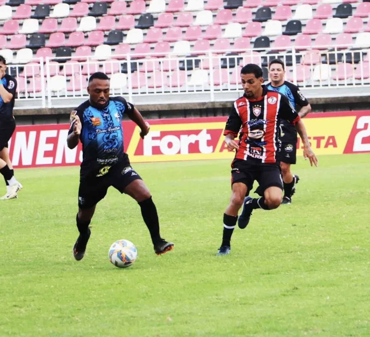 Jogadores disputam a bola em partida de futebol em Joinville