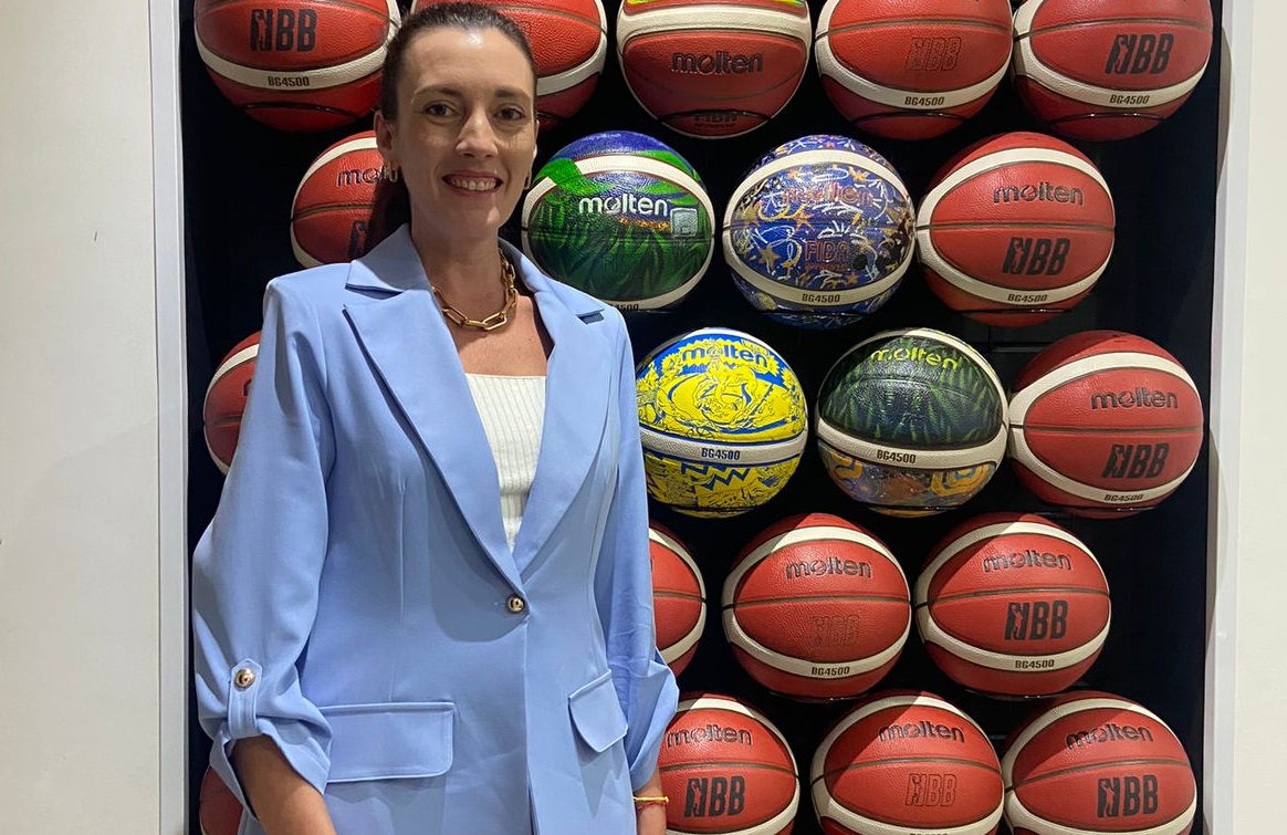 Priscilla Castro diante de uma coleção de bolas de basquete
