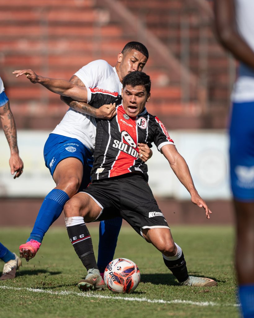 Atleta do Joinville protege a bola em disputa com jogador do Barra